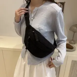 Frau trägt eine schwarze Bauchtasche aus Cord über einem hellblauen Pullover