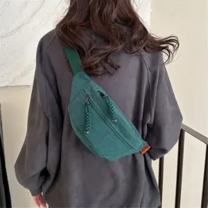 Frau trägt eine grüne Bauchtasche aus Cord schräg über dem Rücken