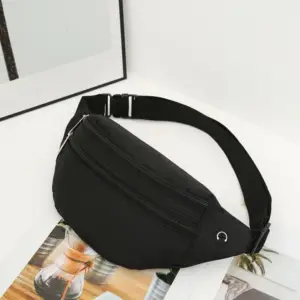 Schwarze Bauchtasche aus Stoff mit zwei Reißverschlüssen liegt in einer hellen Ecke