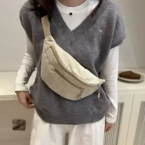 Creme-beige Cord-Bauchtasche, von einer Frau vor dem Körper getragen