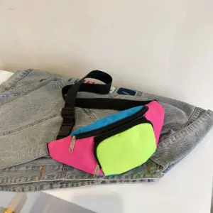 Bunte Bauchtasche in Pink, Blau und Neongrün liegt auf einer Jeansjacke